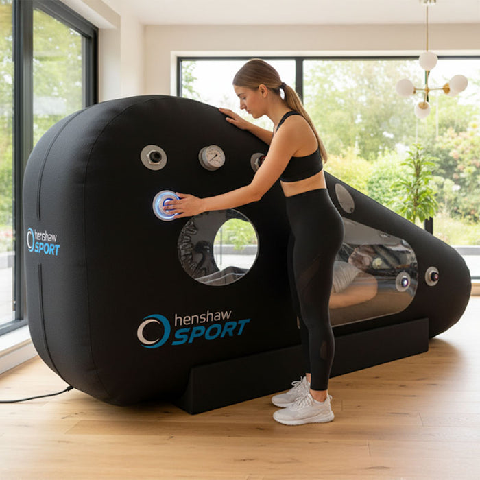 Active woman operating the Henshaw Recline XL Sport Hyperbaric Chamber while another user relaxes inside during therapy.