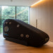 Calm recovery setting with woman seated next to the Henshaw Recline XL Sport Hyperbaric Oxygen Chamber in a private wellness room.