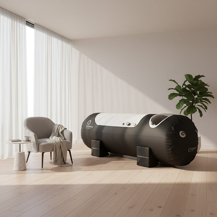 Henshaw Solo Hyperbaric Oxygen Chamber in a modern home therapy room with armchair and tablet, ideal for wellness, recovery, and oxygen therapy.