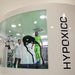 Hypoxico Full Climate Hypoxic Chamber with athlete in green kit on Woodway treadmill inside glass-walled enclosure, supervised by technician in white lab coat.