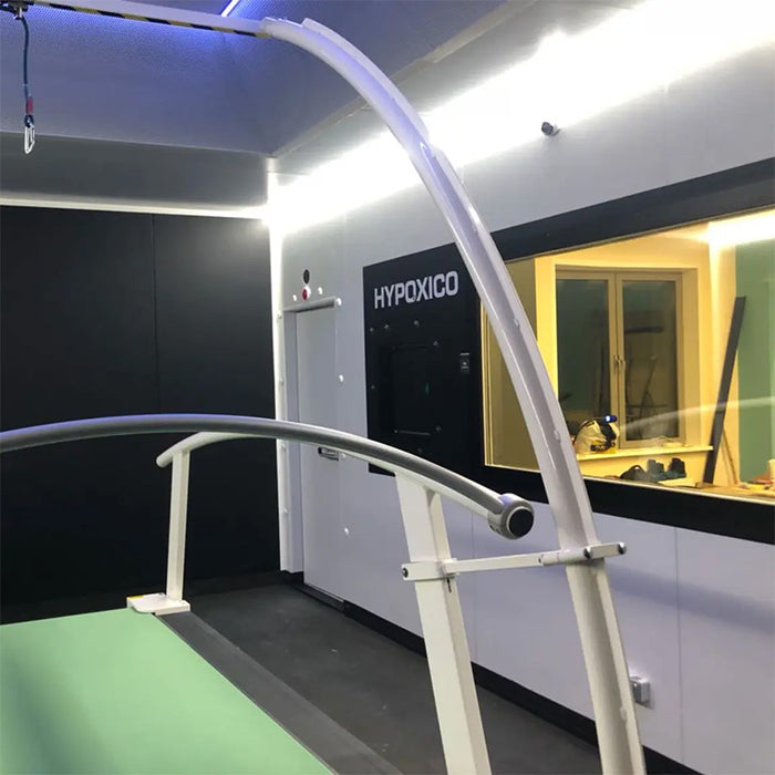Hypoxico Full Climate Hypoxic Chamber standalone pod unit in black angular casing with red and grey accents, showing plus 50 and minus 25 degree temperature range and 10 percent O2 marking, with exercise equipment visible inside through glass door.