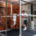 Hypoxico Hypoxic Altitude Chamber acrylic portable pod with aluminium frame in a boxing gym, two athletes sparring inside, boxing posters visible on surrounding walls.