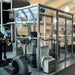 Hypoxico Hypoxic Altitude Chamber acrylic portable pod with aluminium frame in a boxing gym, two athletes sparring inside, boxing posters visible on surrounding walls.
