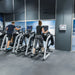 Hypoxico Hypoxic Altitude Chamber altitude room with two athletes on Life Fitness elliptical cross-trainers, wall-mounted display showing 2954m, alpine mountain murals in background.