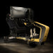 Front three-quarter view of the ImSim TERRA racing simulator in black and gold with ultra-wide monitor stand, racing pedals and cockpit frame.