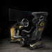 Rear three-quarter view of the ImSim TERRA sim racing cockpit with bucket seat, monitor mount and black and gold chassis.