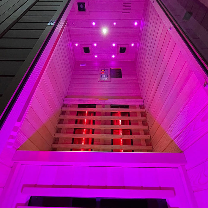 Low-angle shot inside the Insignia KY001 Infrared Indoor Sauna, featuring bright pink lighting and sleek infrared heater panels.