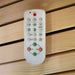 Close-up of the Insignia KY006 Infrared Indoor Sauna remote control, showcasing its easy-to-use buttons for controlling temperature, lighting, and audio.