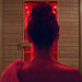 Back view of a woman preparing to enter the Insignia KY008 Infrared Indoor Sauna 1300 x 1000, bathed in warm red infrared glow for personal relaxation.