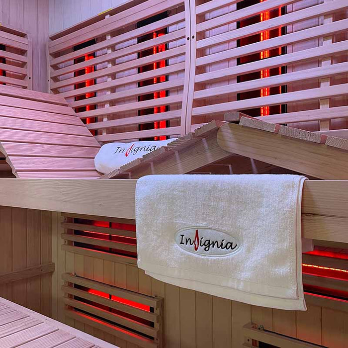 Interior view of the Insignia KY2216 Sauna showcasing the wooden bench, adjustable backrest, and Insignia-branded towel for a luxury experience.