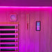 The interior wall of the Insignia Outdoor Hybrid Infrared Sauna 1700 x 1500mm, featuring the digital control panel and a wooden thermometer, with soothing pink LED Chromotherapy lighting illuminating the space.