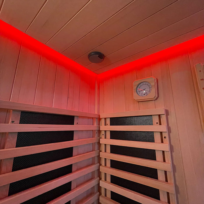 The interior of the Insignia Outdoor Hybrid Infrared Sauna 1700 x 1500mm, featuring warm red LED Chromotherapy lighting, handcrafted Canadian Hemlock wood walls, and built-in infrared panels for optimal heat distribution.