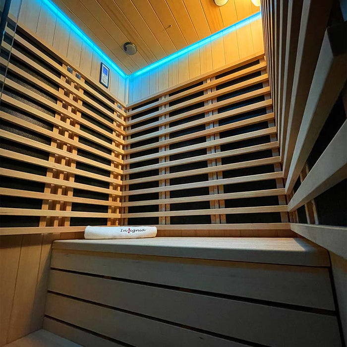 A cosy seating area inside the Insignia Outdoor Infrared Sauna 1500 x 1300mm with blue LED chromotherapy lighting, showcasing the comfortable wooden bench and sleek interior design.