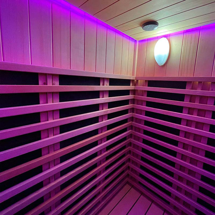 The elegant wooden interior of the Insignia Outdoor Infrared Sauna 1500 x 1300mm illuminated by soothing pink chromotherapy lighting, creating a relaxing and inviting atmosphere.