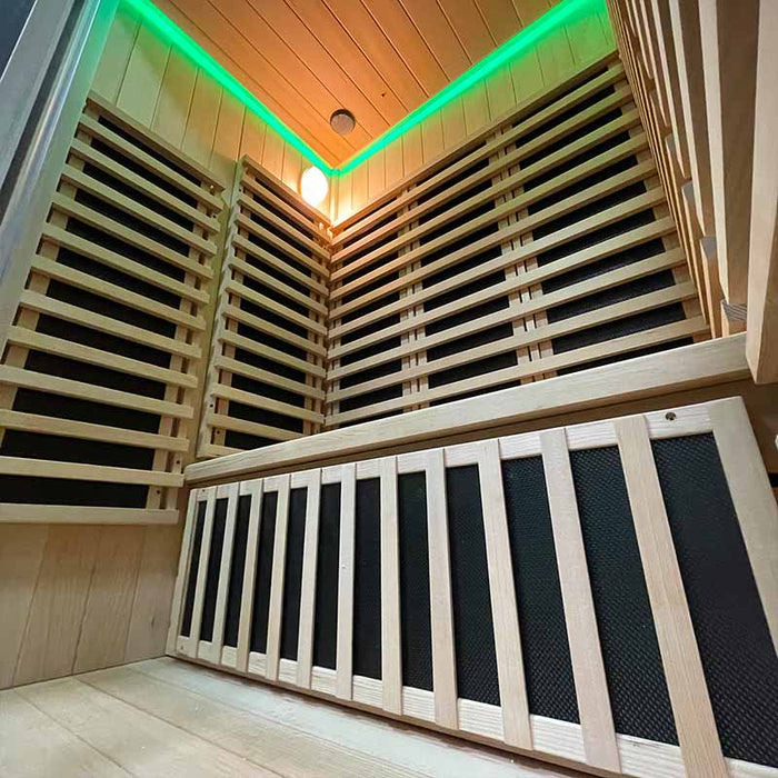 Green chromotherapy lighting illuminating the wooden bench and heater panels inside the Insignia Outdoor Infrared Sauna 1500 x 1300mm, creating a calming and energising environment.