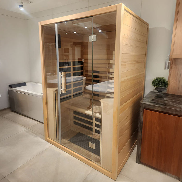 Jaquar Paire 2-person infrared sauna on display in a modern showroom, highlighting its compact wooden exterior and transparent glass door.
