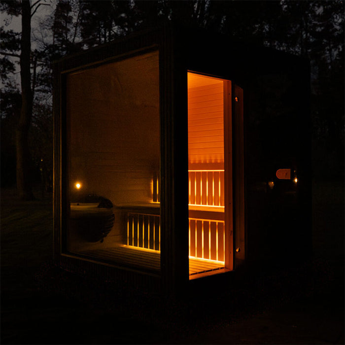 Night-time exterior angle of the Jonas Classic 4-person garden sauna with door open, revealing warm-lit wooden interior.