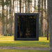 Front view of the Jonas Classic 4-person outdoor sauna in woodland clearing, featuring large mirrored glass façade.