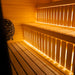 Interior view of the Jonas Classic 4-person outdoor sauna featuring natural timber benches, LED strip lighting, and HUUM stone heater.