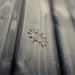 Brushed timber exterior wall of the Jonas Classic outdoor sauna with subtle engraved sun emblem detail.
