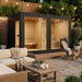 Stylish black Jonas Grand 8–10 person lounge sauna featured in a cosy backyard setting with string lights, fire pit, and outdoor lounge furniture.