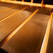 Close-up of smooth wooden sauna bench slats inside the Jonas Grand 8-person outdoor sauna with warm under-bench lighting.