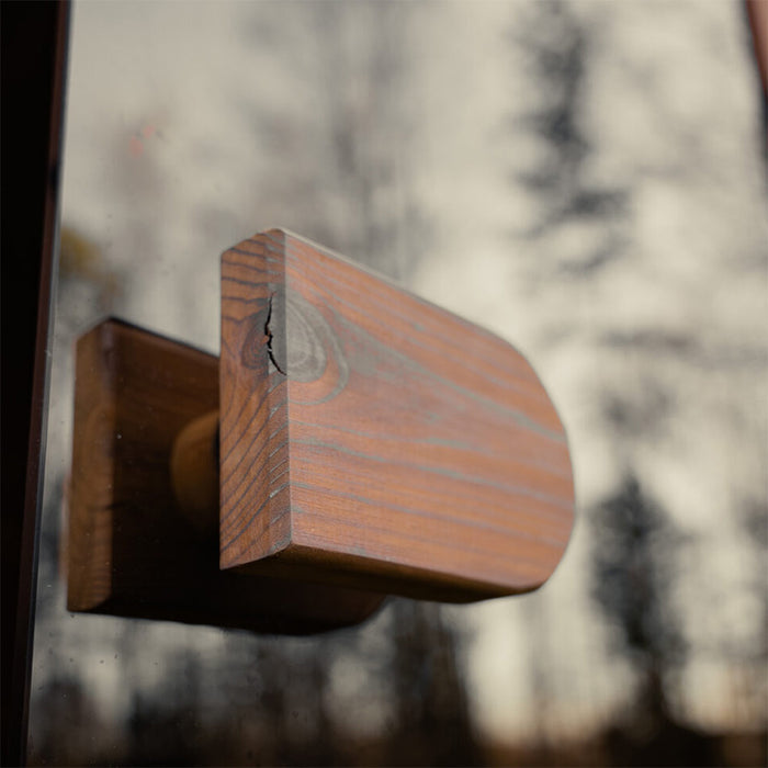 Close-up of the exterior wooden door handle on the Jonas Grand 8-person outdoor sauna, mounted on a reflective glass door.