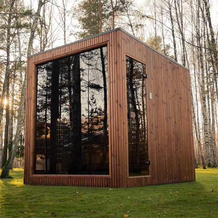 Jonas Grand 8-person outdoor sauna in a tranquil forest setting with natural light reflecting off the tinted glass panels.