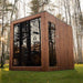 Jonas Grand 8-person outdoor sauna in a tranquil forest setting with natural light reflecting off the tinted glass panels.