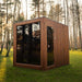 Full exterior shot of the Jonas Grand 8-person outdoor sauna placed on a lush green lawn with tall trees in the background.