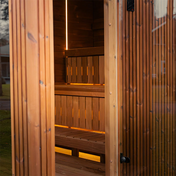 Open door view into the Jonas Grand 8-person sauna revealing inviting warm lighting and precision-crafted timber seating.