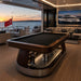 Koralturk Atlantis Gyroscopic Pool Table with dark playing surface and luxury wood finish aboard a superyacht at sunset.