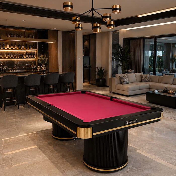 Koralturk Elit Pool Table with vibrant pink cloth, black frame, fluted pedestal bases and gold accents in a luxury games room.