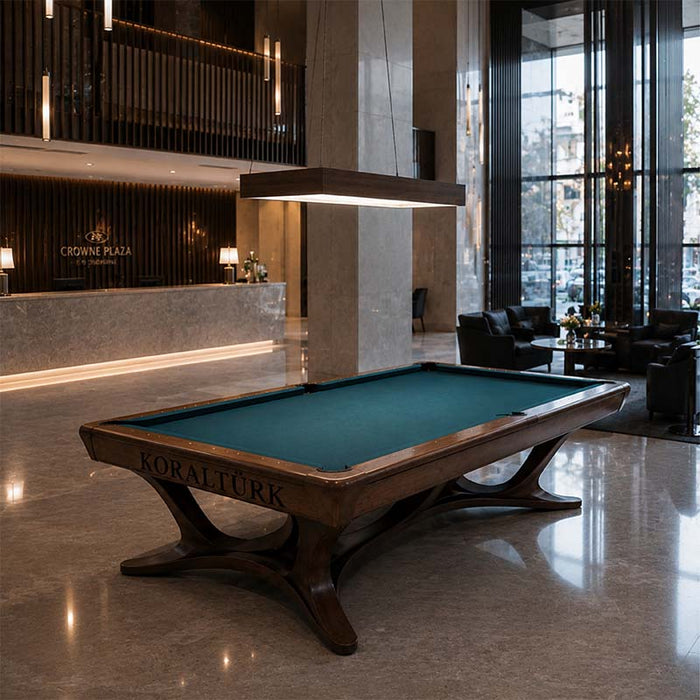 Koralturk Legnora luxury billiards table featuring green playing cloth and curved timber legs in a sophisticated hotel lounge.