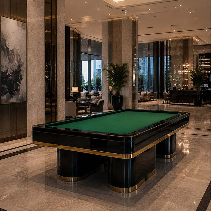 Koralturk Trapeza Pool Table with green cloth, polished black frame and gold accents displayed in an elegant hotel lobby.