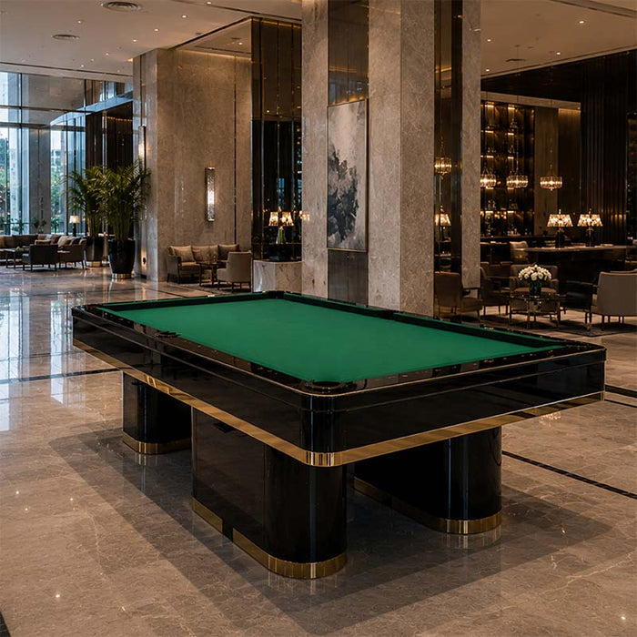 Koralturk Trapeza luxury pool table featuring green playing cloth, bold black pedestal legs and gold trim in a sophisticated hotel interior.