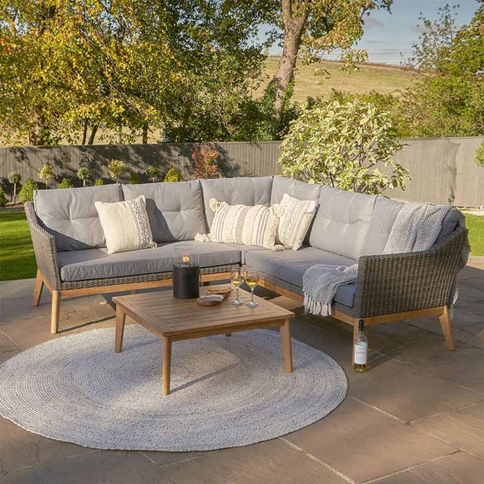 Larissa Outdoor Corner Seating Set arranged in a garden setting with a wooden coffee table, showcasing its rattan design and comfortable cushions.