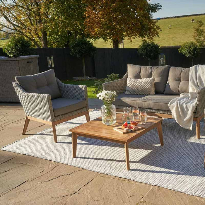 Close-up view of Larissa Outdoor Seating Set in garden with drinks, flowers and blanket.