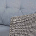 A detailed shot of the Larissa Outdoor Seating Set armrest, focusing on the rattan weave and the plush grey cushion.