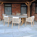 A stylish outdoor Luna 6 Seater Concrete Table Dining Set featuring a round concrete dining table and six cushioned chairs, creating an inviting alfresco dining space under a covered patio.