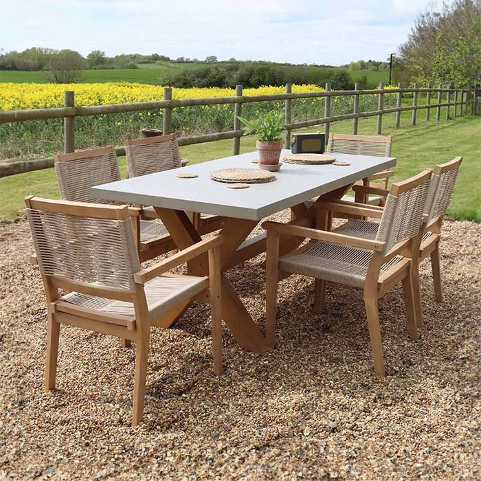 Left-angle shot of the Luna 6 Seater Rectangular Concrete Dining Set, highlighting the concrete table and rope chairs in a beautiful garden setting.