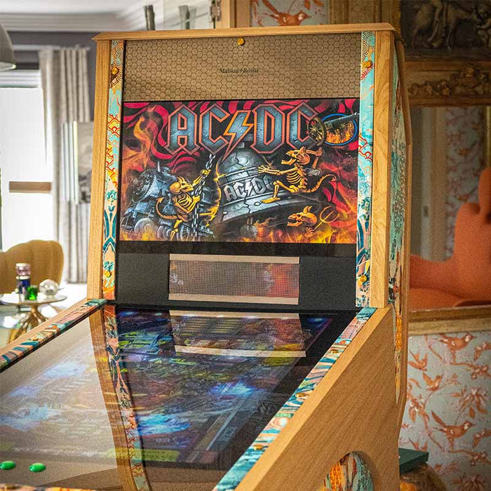 Maison Roshi Jiraiya Pinball Machine displaying AC/DC themed game artwork on backglass with vibrant patterned trim and wooden frame.