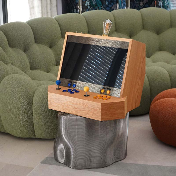 Maison Roshi Sensei V1 arcade console with vibrant blue and yellow controls, set atop a sculptural metallic base, blending vintage gaming with modern interior style.