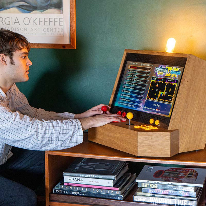 Maison Roshi Sensei V1 retro arcade console with yellow and red joysticks, in use by a player scrolling through Pandora’s Box game menu in a home gaming setup.