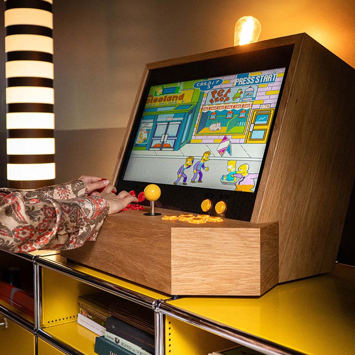Maison Roshi Sensei V1 classic arcade cabinet with The Simpsons game, red and yellow controls, and signature wooden build set on a stylish yellow shelf.