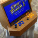 Close-up of Maison Roshi Sensei V1 playing Street Fighter II, featuring blue and orange buttons on a sleek wooden arcade cabinet with nostalgic gaming visuals.