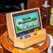 Maison Roshi Sensei V1 arcade machine playing Super Mario World, featuring blue and orange buttons on a handcrafted wooden frame with vintage-style lighting.