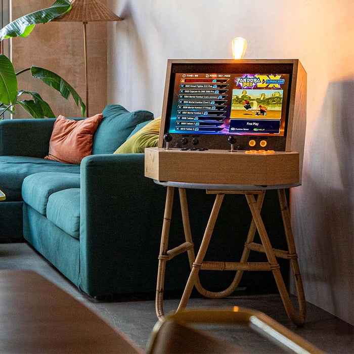 Maison Roshi Sensei V2 arcade machine running Pandora’s Box, placed beside a teal sofa with black joysticks and signature handcrafted oak casing.