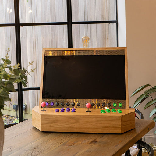 Maison Roshi Sensei V3 home arcade cabinet with a sleek blank screen and dual player controls, displayed on a wooden dining table.