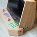 Close-up angled shot of Maison Roshi Sensei V3 arcade system, showing LED-lit buttons, pink joysticks, and detailed wood craftsmanship.